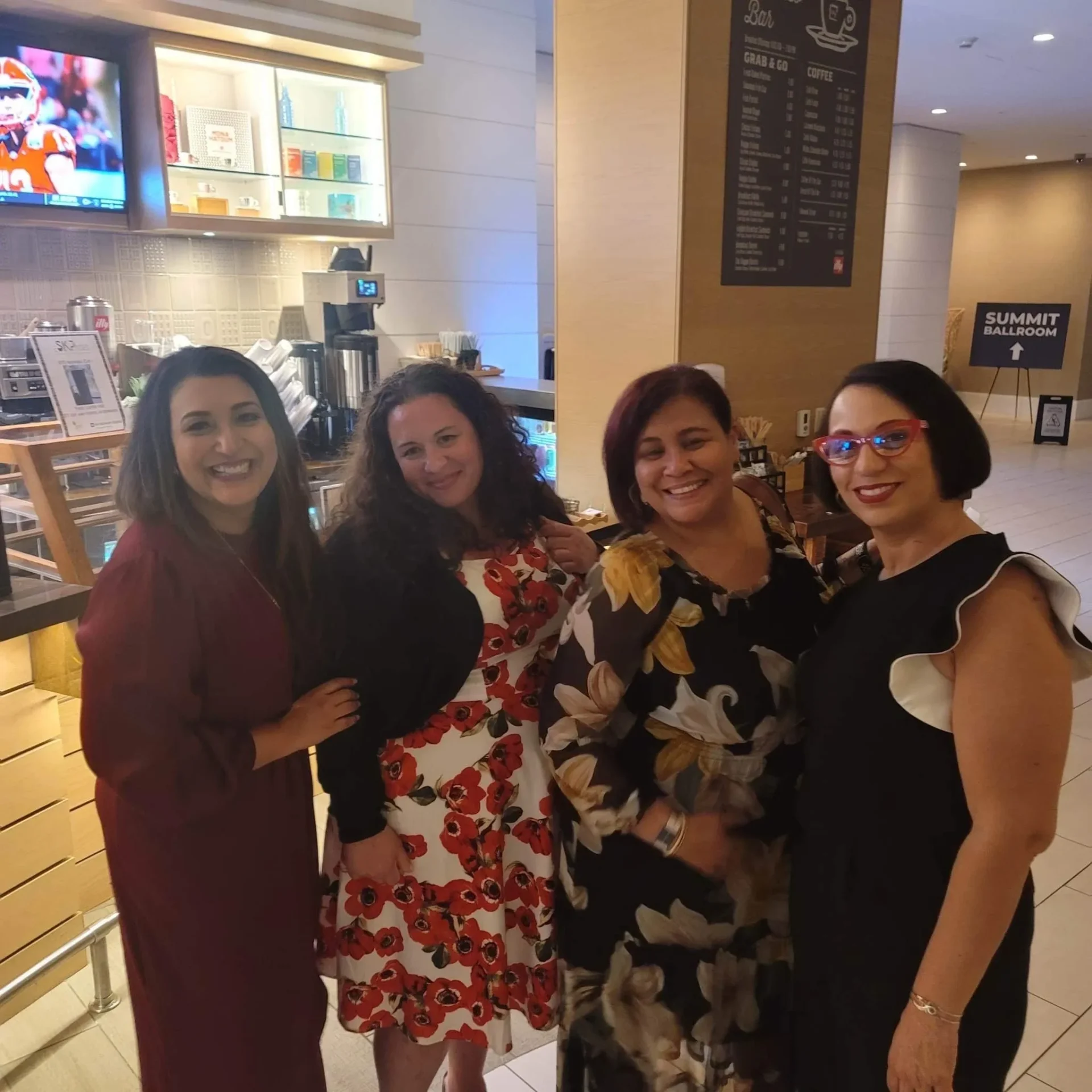 Four women in dresses posing for a picture.